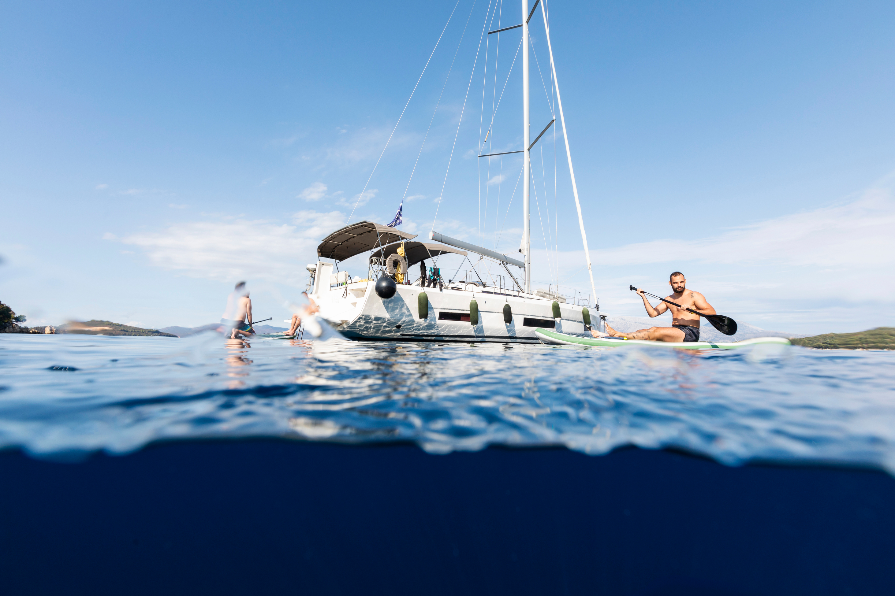 man on paddleboat with sailboat